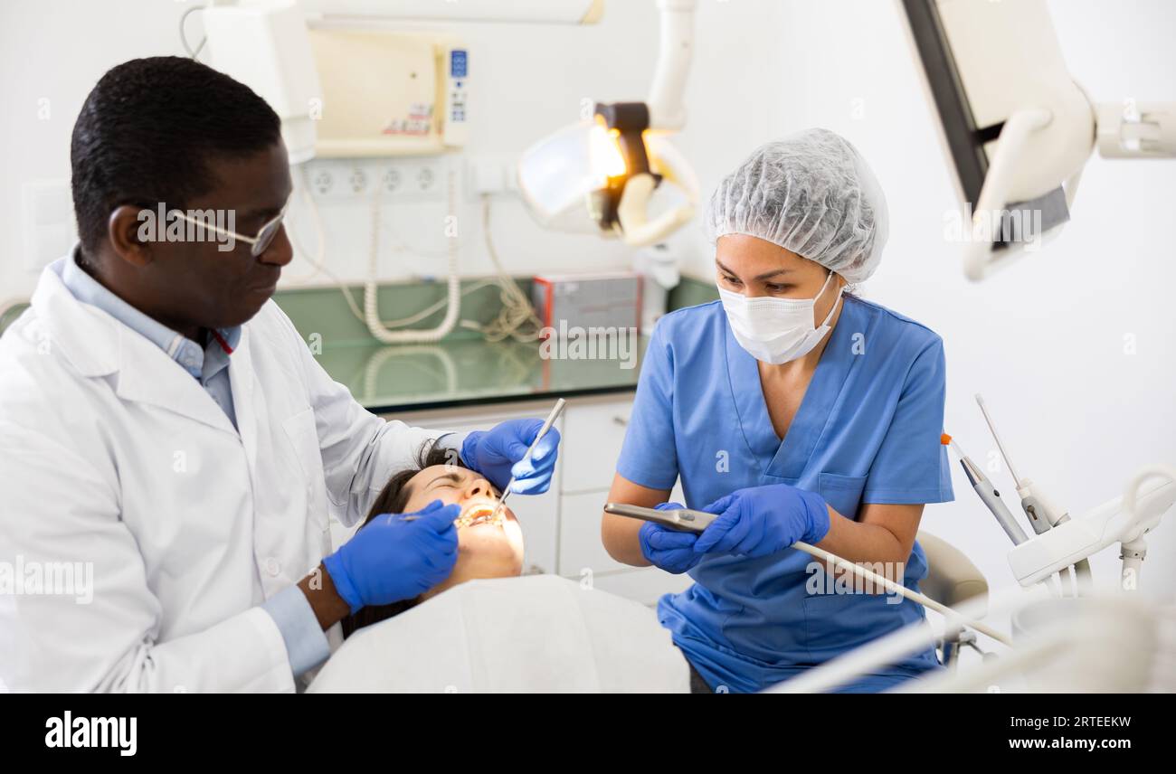 Dentist and nurse performing tooth enamel restoration operation on