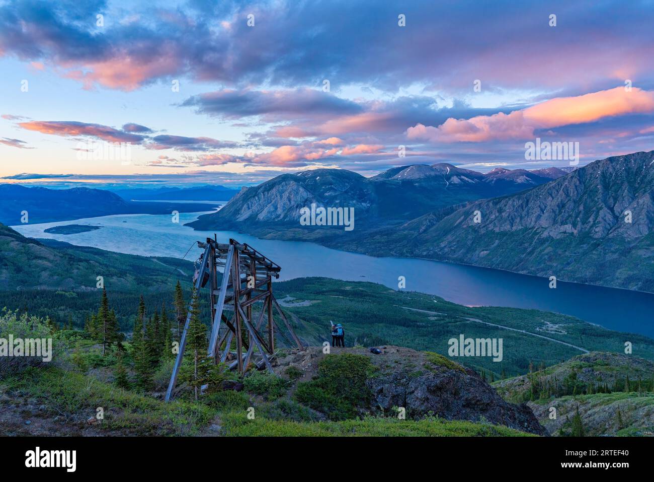 Two women standing on a mountain top next to a mining relic on Montana Mountain, enjoying the view while exploring and photographing the amazing sc... Stock Photo