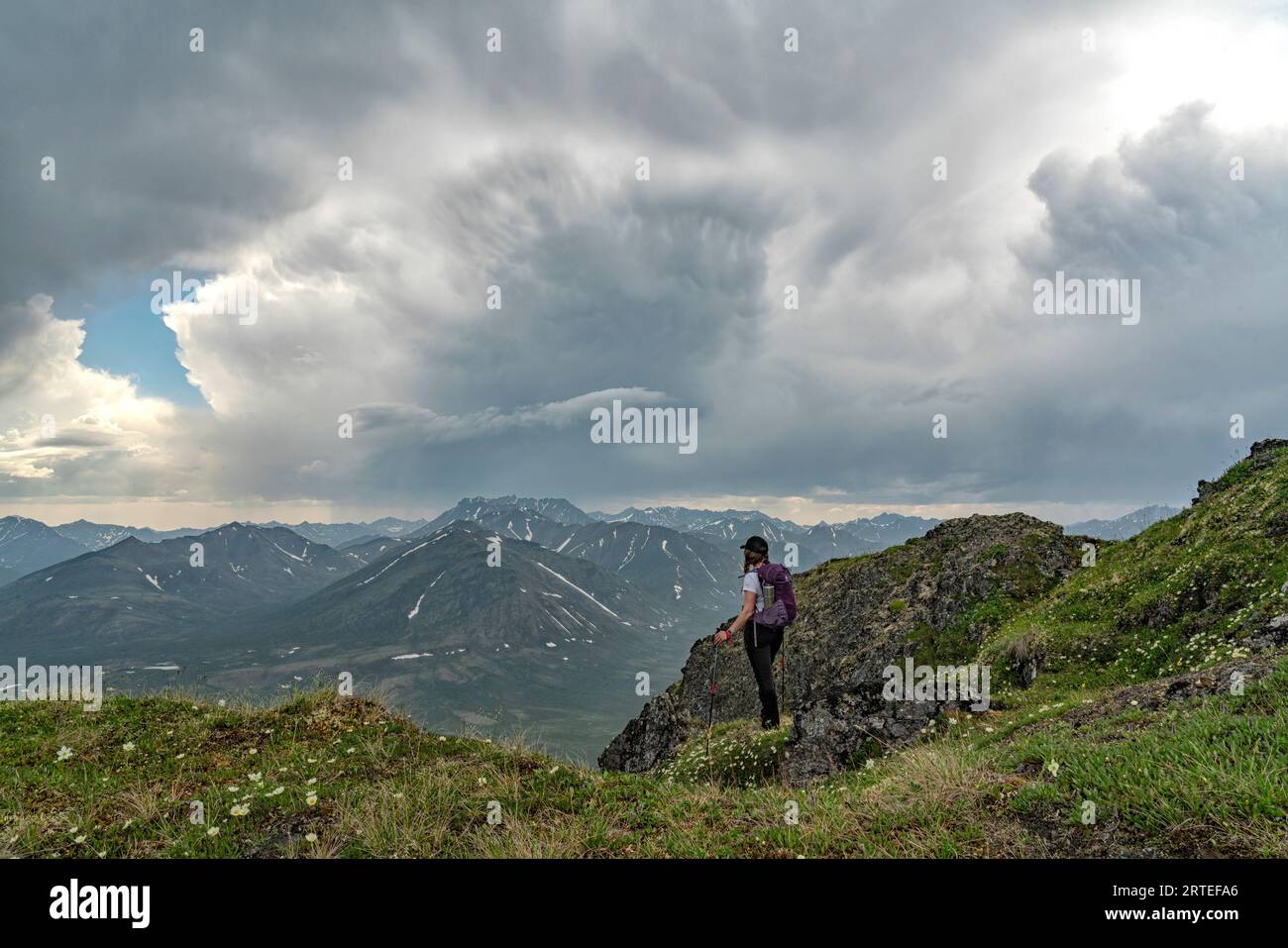 Woman standing on a mountain side overlooking the Upper Blackstone Valley in Northern Yukon looking out at the beautiful views along the Dempster H... Stock Photo