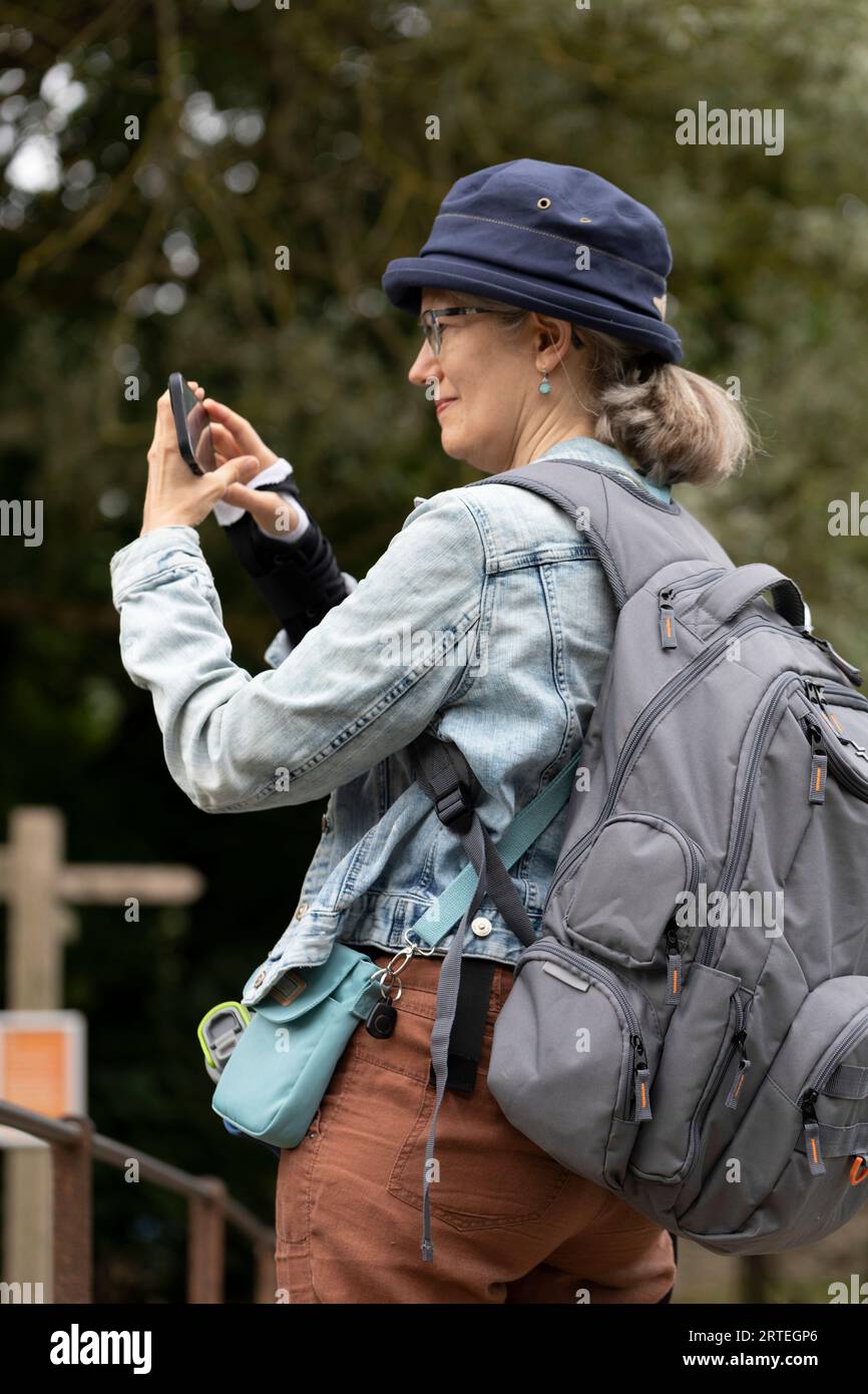 Mature woman uses her smart phone while travelling outdoors; United Kingdom Stock Photo