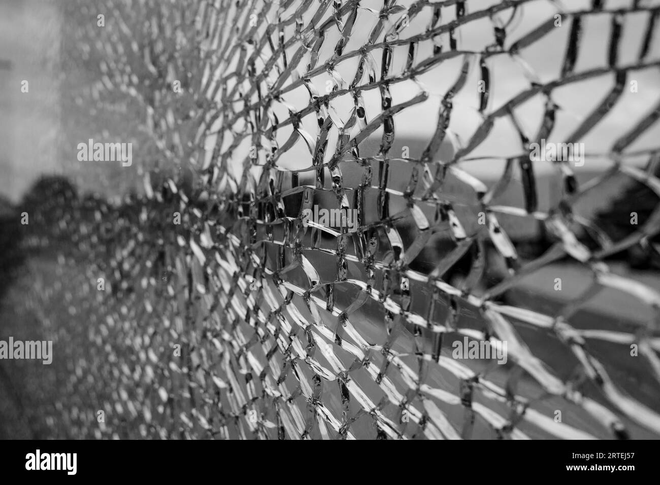 Black and white tone, Selective focus, broken crack glass window and blur background of the city and sidewalk. Stock Photo