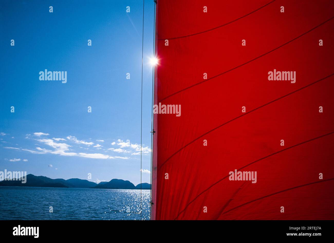 Sunlight and a red mainsail on Prince William Sound, Alaska, USA; Alaska, United States of America Stock Photo