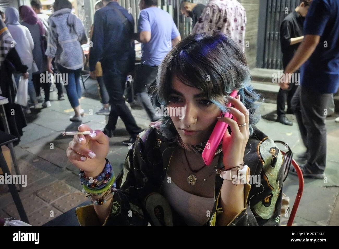 Tehran, Iran. 12th Sep, 2023. An Iranian young girl talks with her mobile  phone while smoking a cigarette at a cafe beside Enghelab (Revolution)  Street in downtown Tehran. A year after the