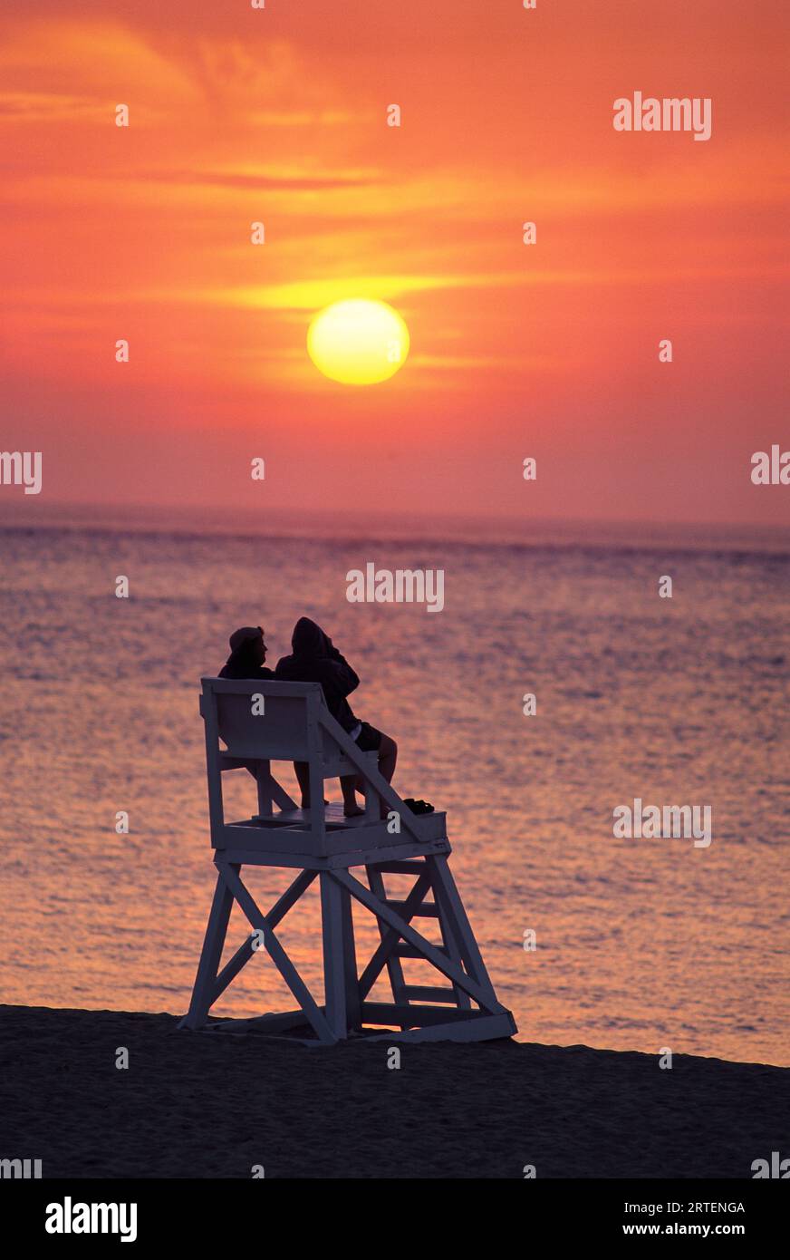 Pair of lifeguards watch the sunset at Race Point Beach, Cape Cod, Massachusetts, USA; Cape Cod, Massachusetts, United States of America Stock Photo