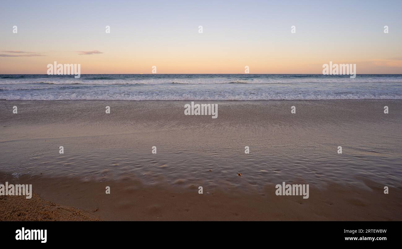 Looking east over the Pacific Ocean, Queensland, as the sun sets in the west, waiting for the full moon to rise above the horizon while the surf waves Stock Photo