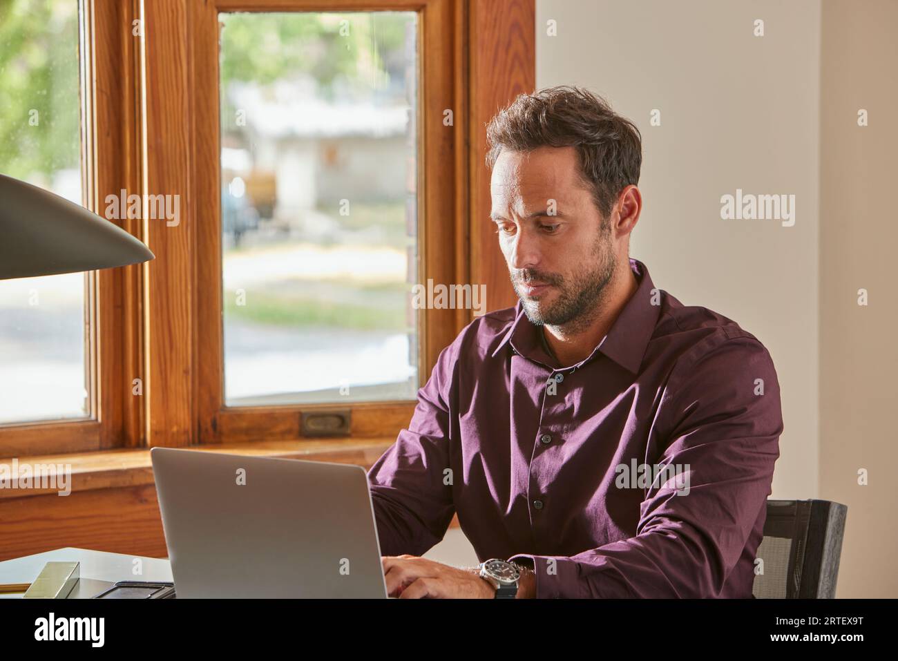 Man using laptop at desk at home Stock Photo