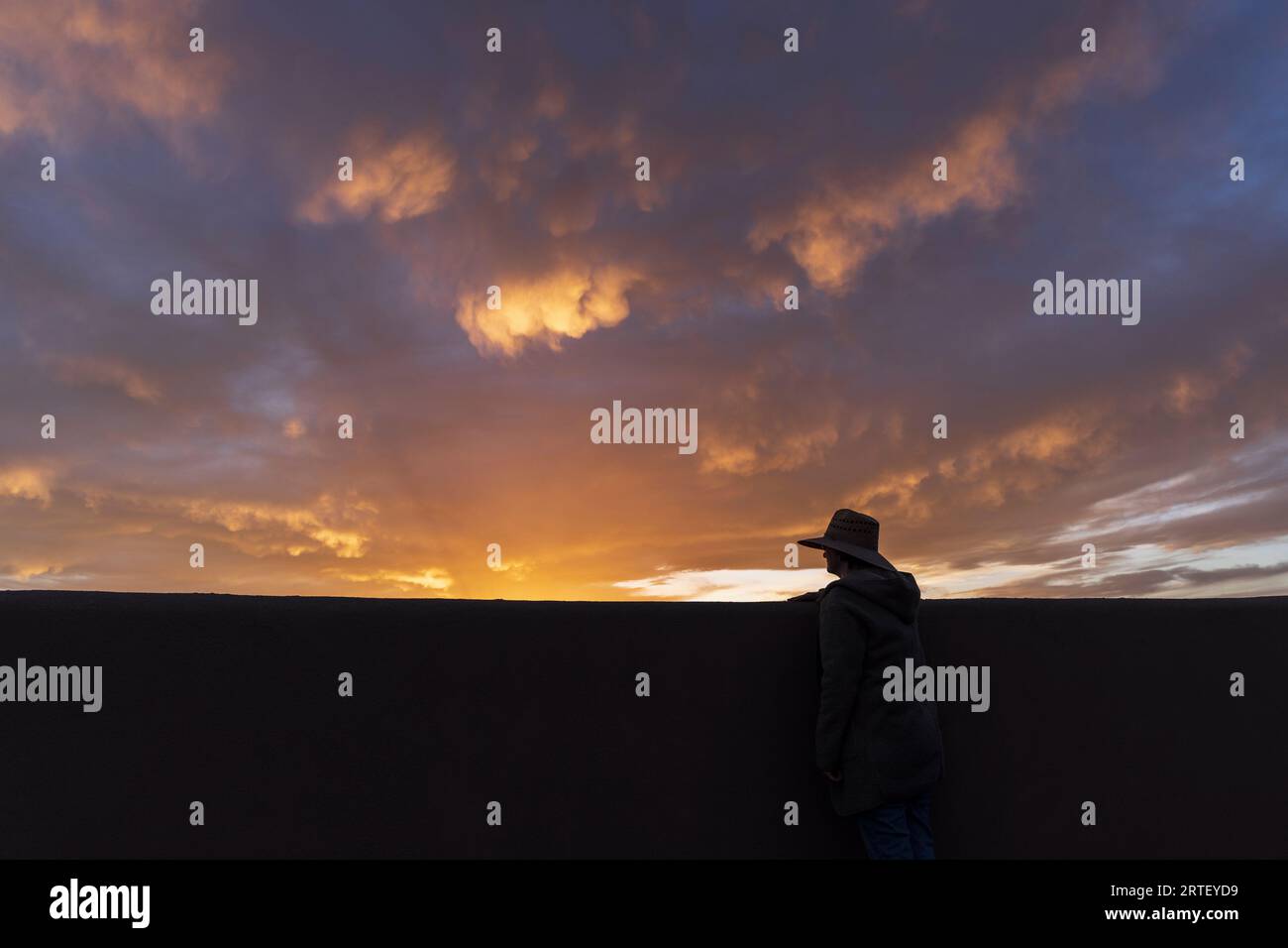 Silhouette of man in hat looking at sunset Stock Photo