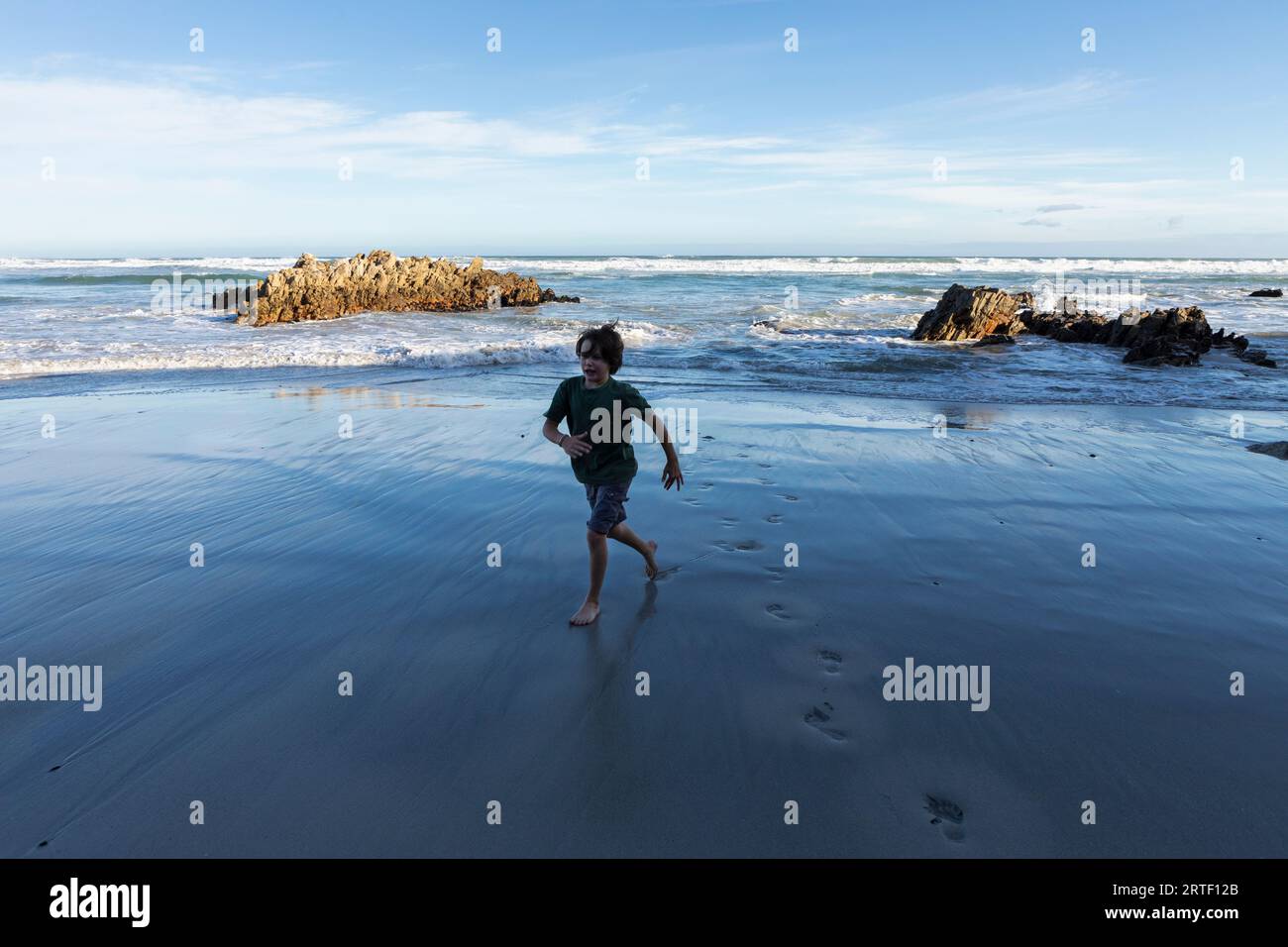 South Africa, Hermanus, Boy (10-11) running on Voelklip Beach Stock Photo