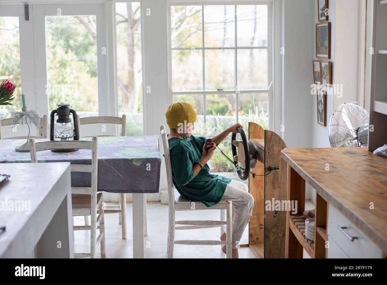 Boy (10-11) pretending to drive homemade steering wheel at home Stock Photo