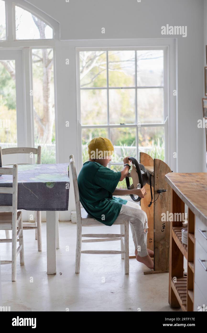 Boy (10-11) pretending to drive homemade steering wheel at home Stock Photo