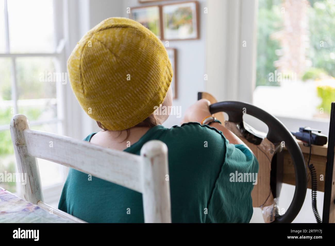 Rear view of boy (10-11) pretending to drive homemade steering wheel at home Stock Photo