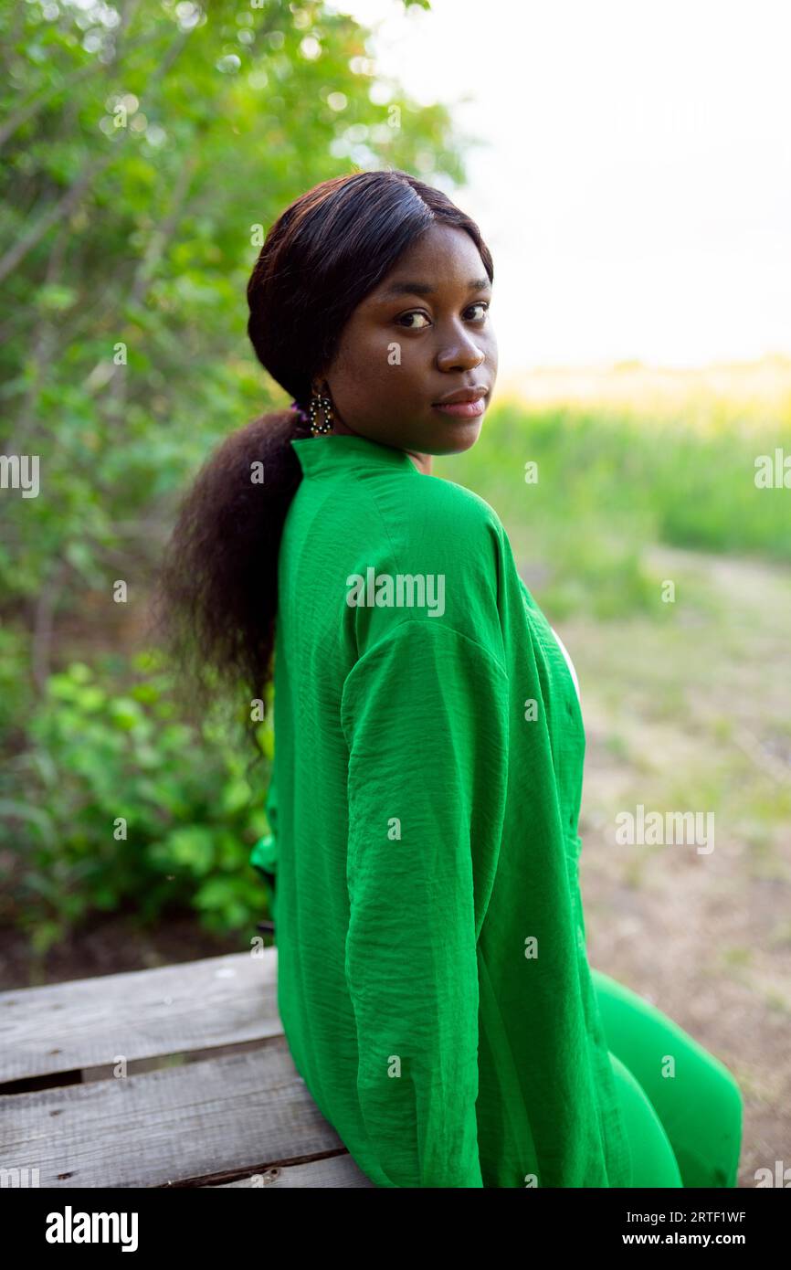 Woman wearing green blouse, looking over shoulder Stock Photo