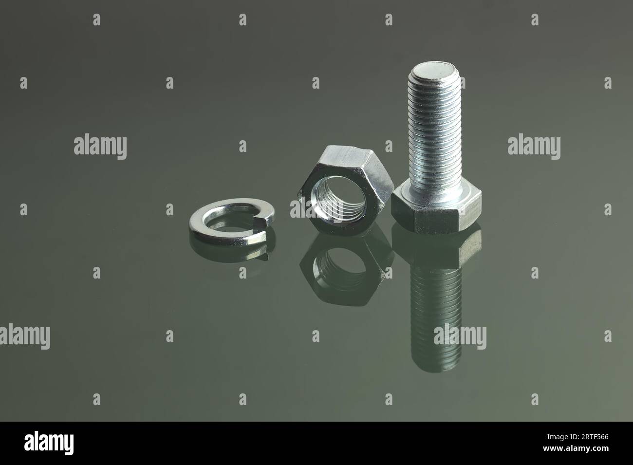 Detailed view of a bolt, nut and spring washer placed on a reflective