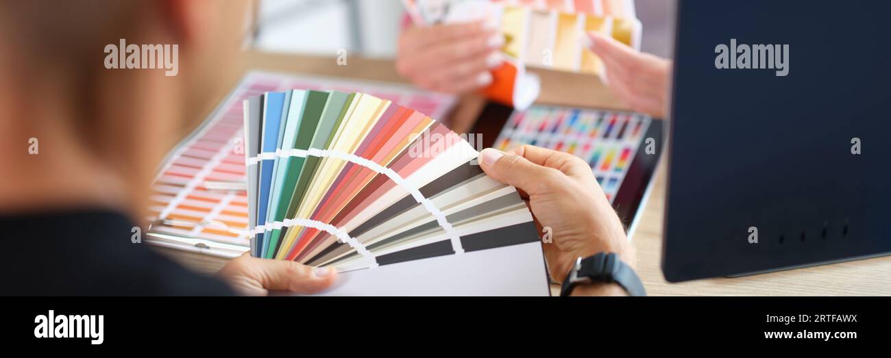 Manager and client holding color swatch cards while sitting at table in ...