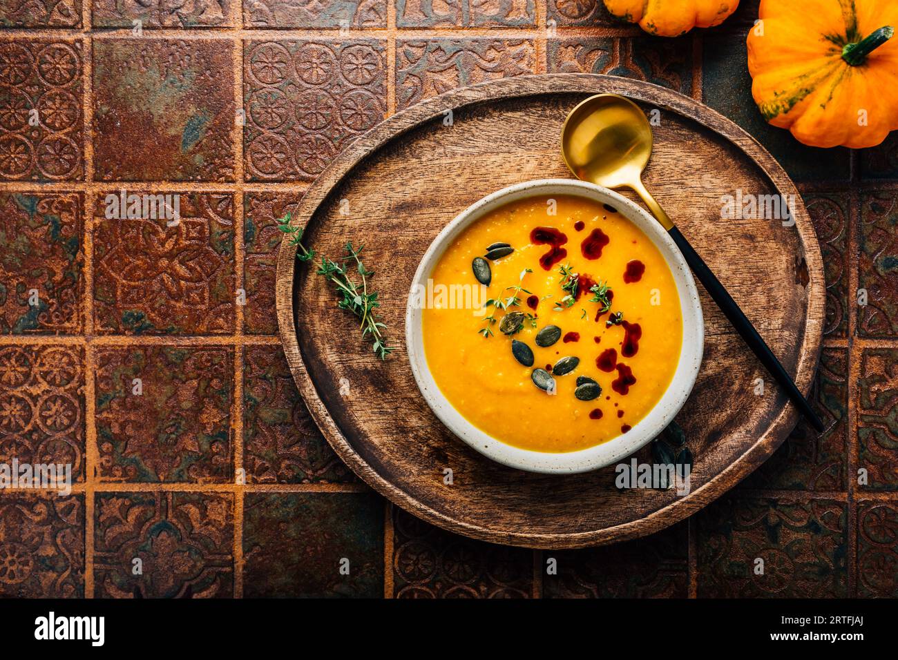 Pumpkin soup with pumpkin seeds  and pumpkin seed oil served in bowl on rustic kitchen table Stock Photo