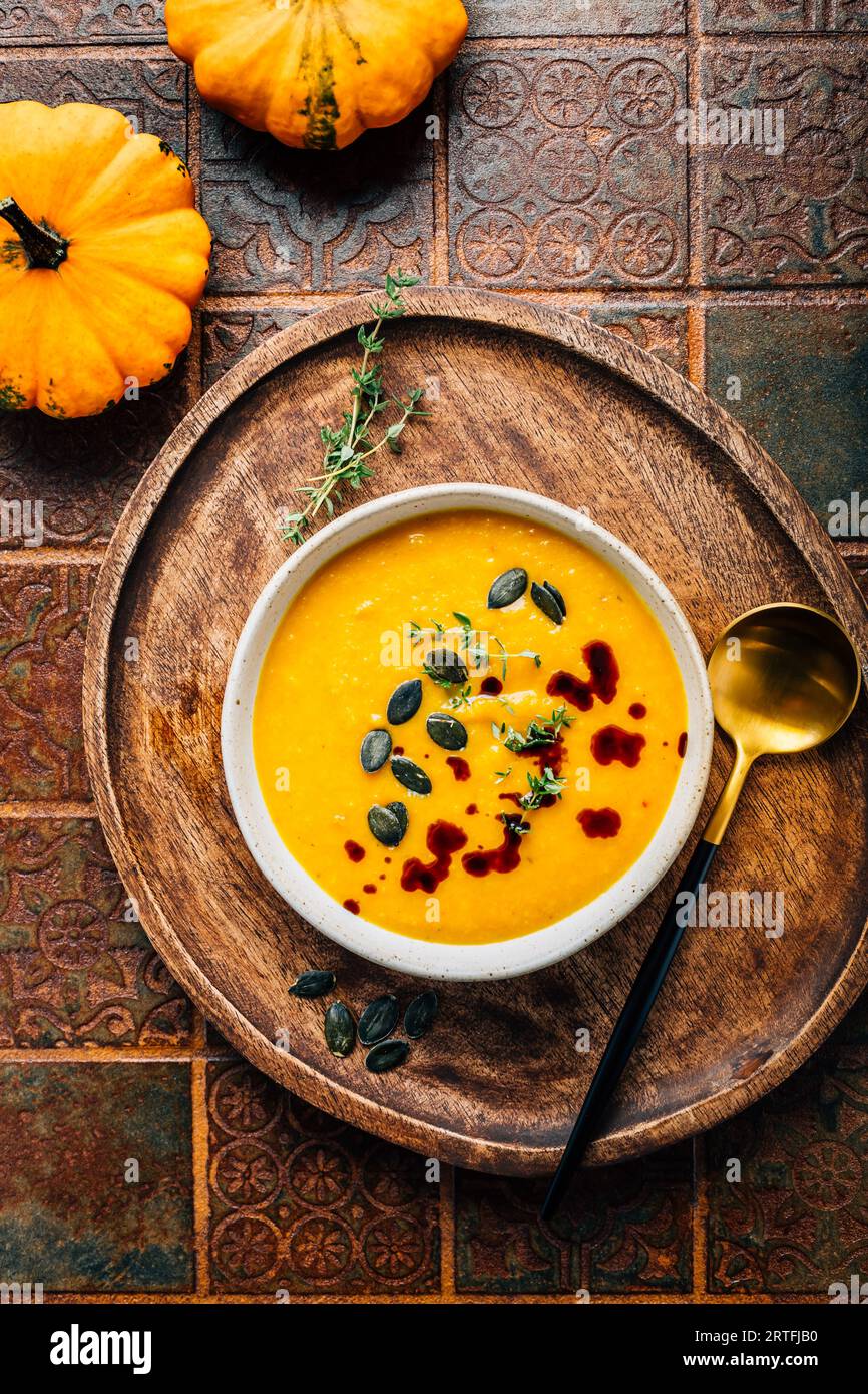 Pumpkin soup with pumpkin seeds  and pumpkin seed oil served in bowl on rustic kitchen table Stock Photo