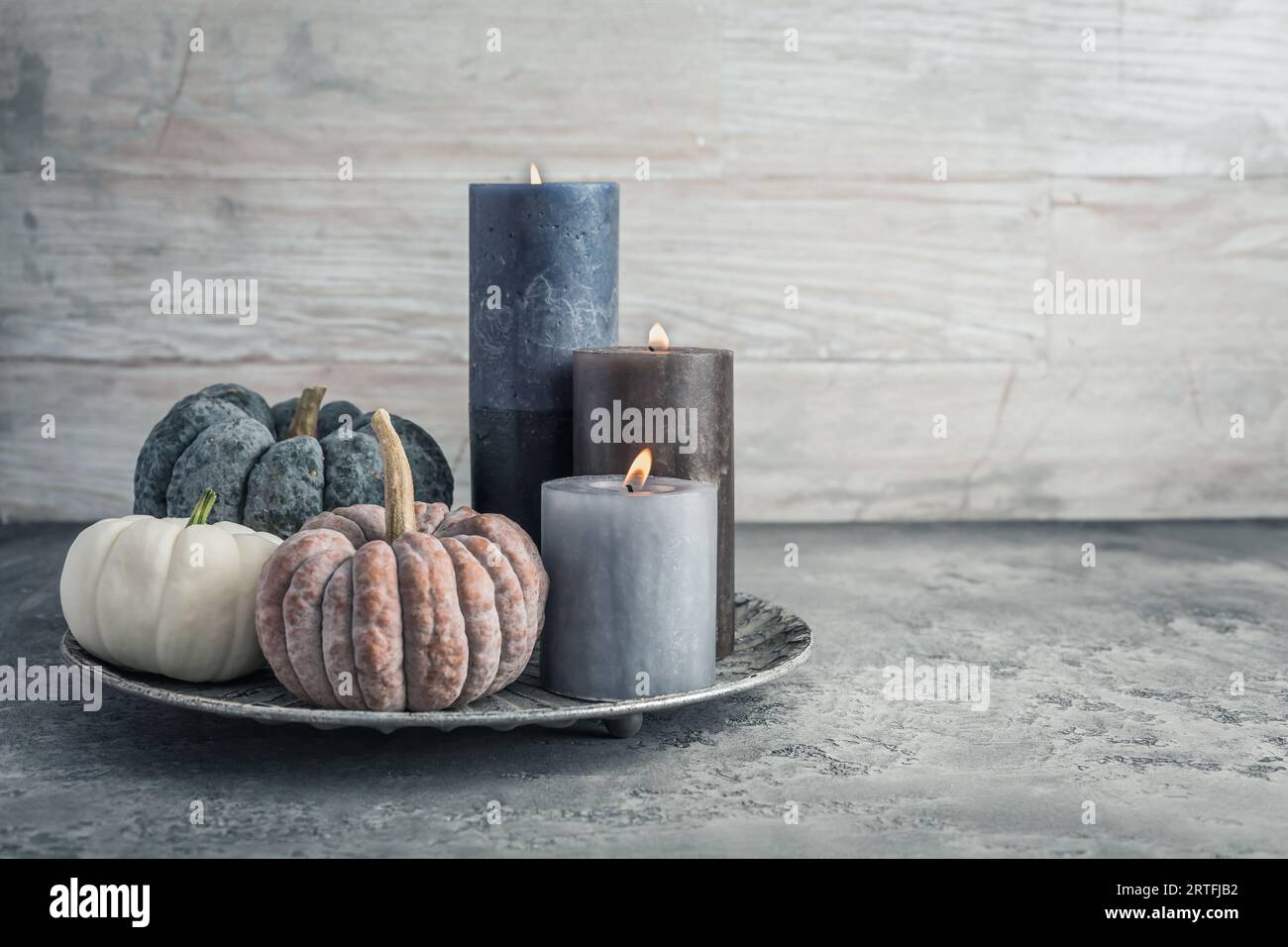 Autumn fall cozy mood composition for hygge home decor.  Candles and pumpkins for Thanksgiving in grey tone Stock Photo