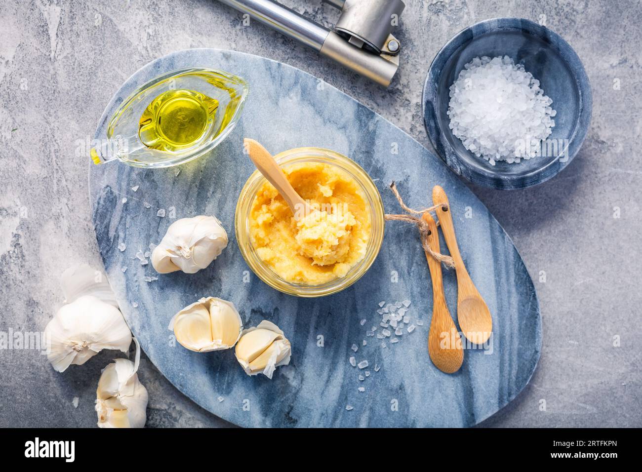 Homemade garlic paste in a jar with peeled garlic, salt, crusher and garlic heads. Stock Photo