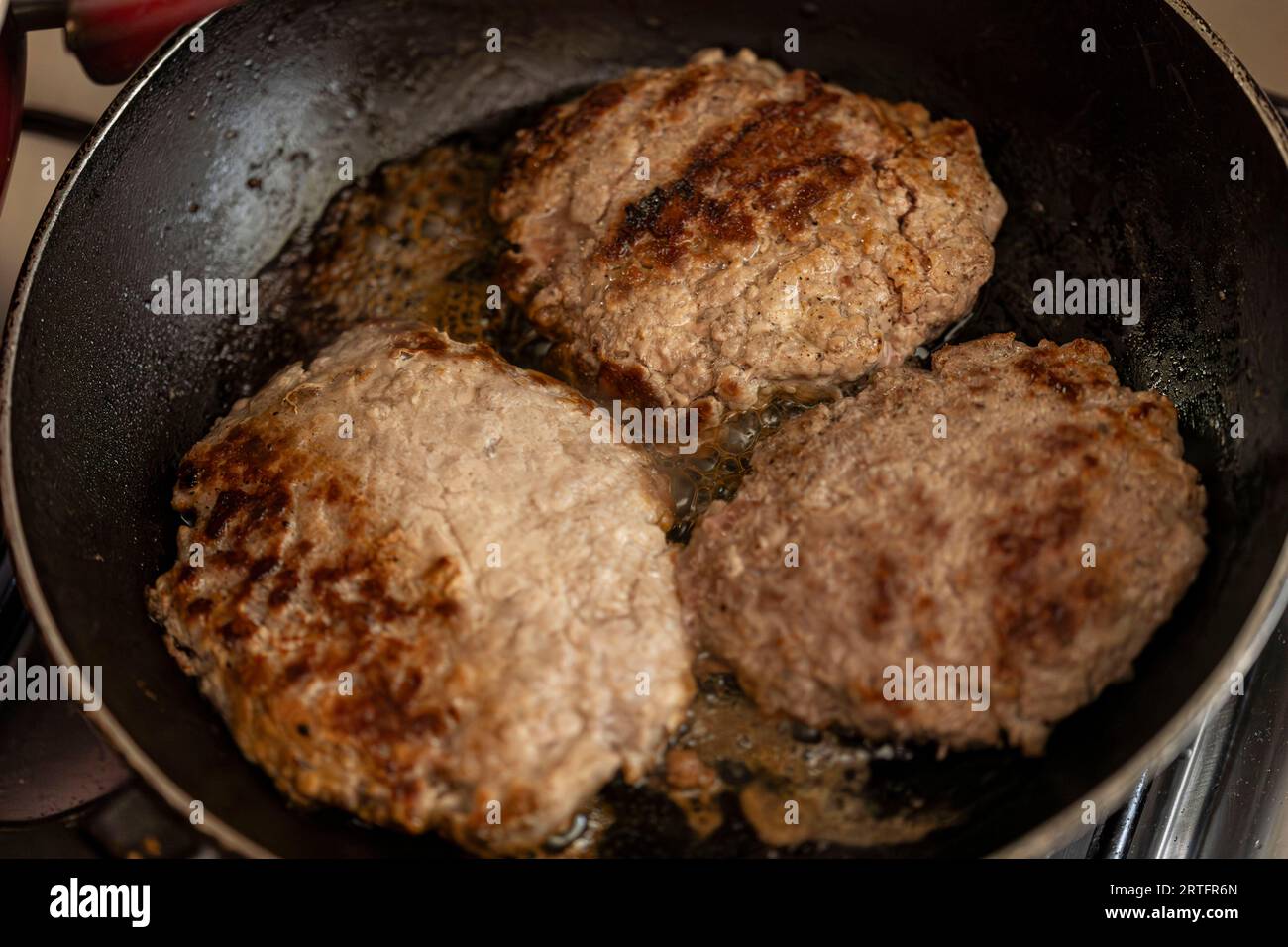 Capturing the moment of a juicy hamburger patty sizzling on a pan atop