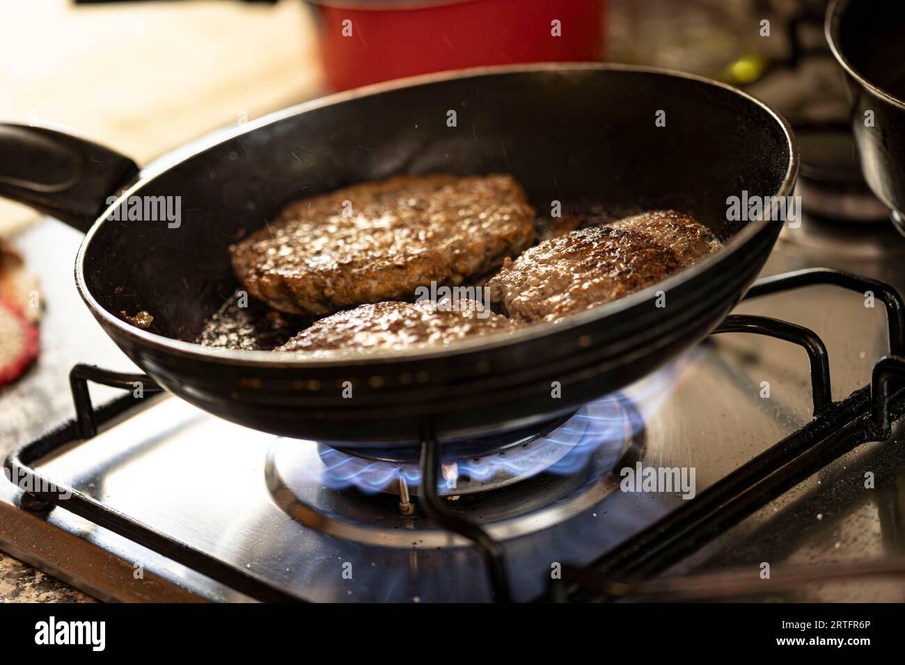 Capturing the moment of a juicy hamburger patty sizzling on a pan atop