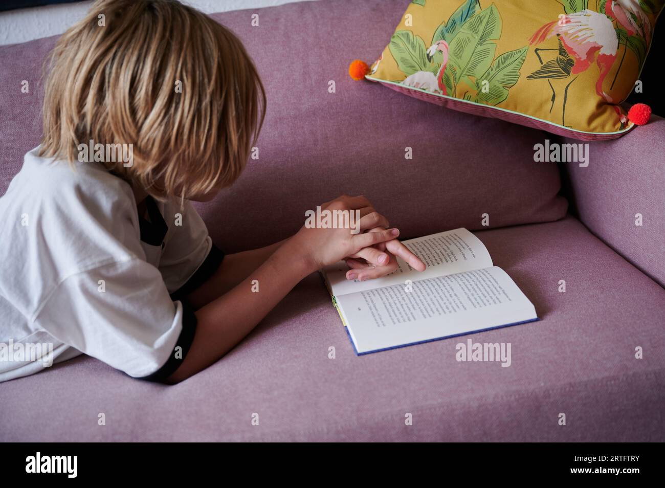 Berlin, Germany. 26th Aug, 2023. A child is reading while lying on the couch. (posed scene) Credit: Annette Riedl/dpa/Alamy Live News Stock Photo