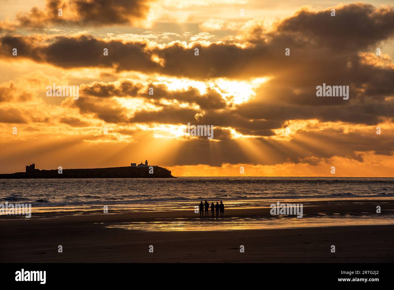 Bamburgh, Northumberland, UK. 13th September 2023. A group of people watch the sunrise over the Farne Islands from Bamburgh beach, Northumberland. Neil Squires/Alamy Live News Stock Photo
