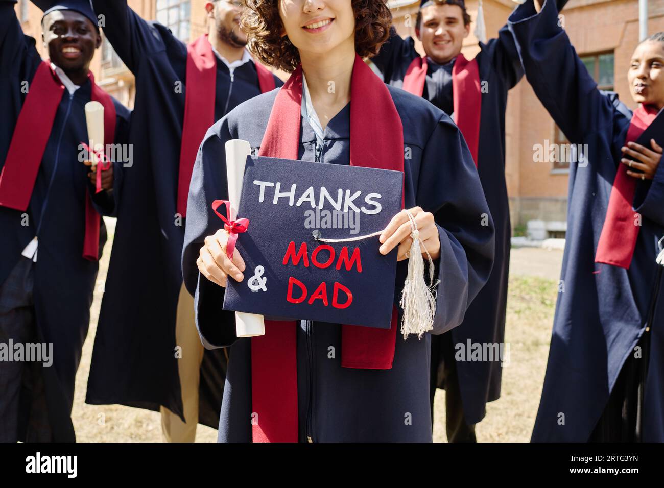 Portrait of graduate teen latin boy student in black graduation gown with  hat, holding diploma - isolated on background. Child back to school and  educational concept. Stock Photo