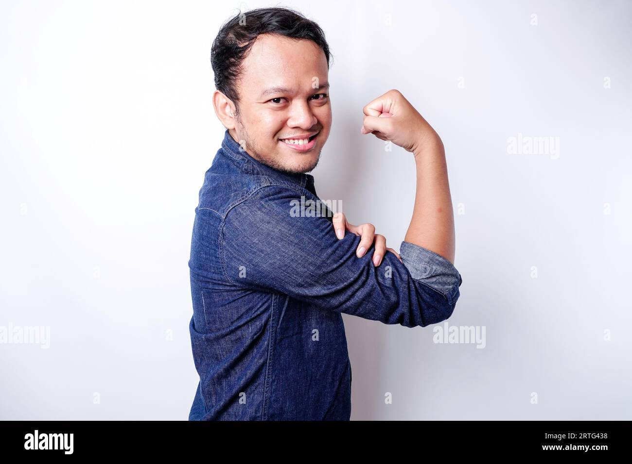 Excited Asian man wearing a blue shirt showing strong gesture by ...
