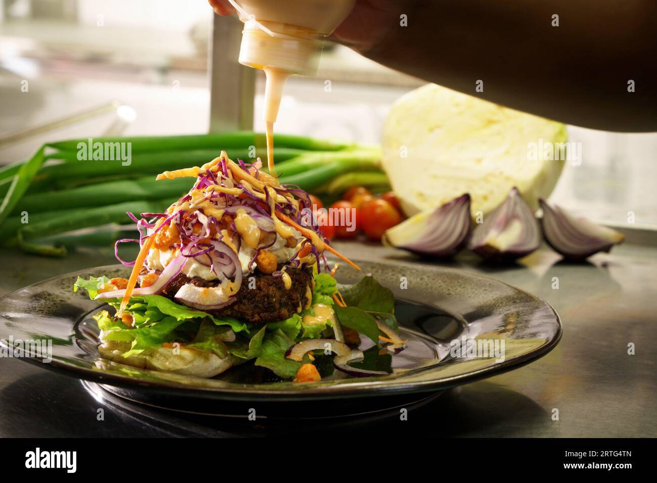 hamburger meal plated showing hand positioning garnishings and sauce Stock Photo