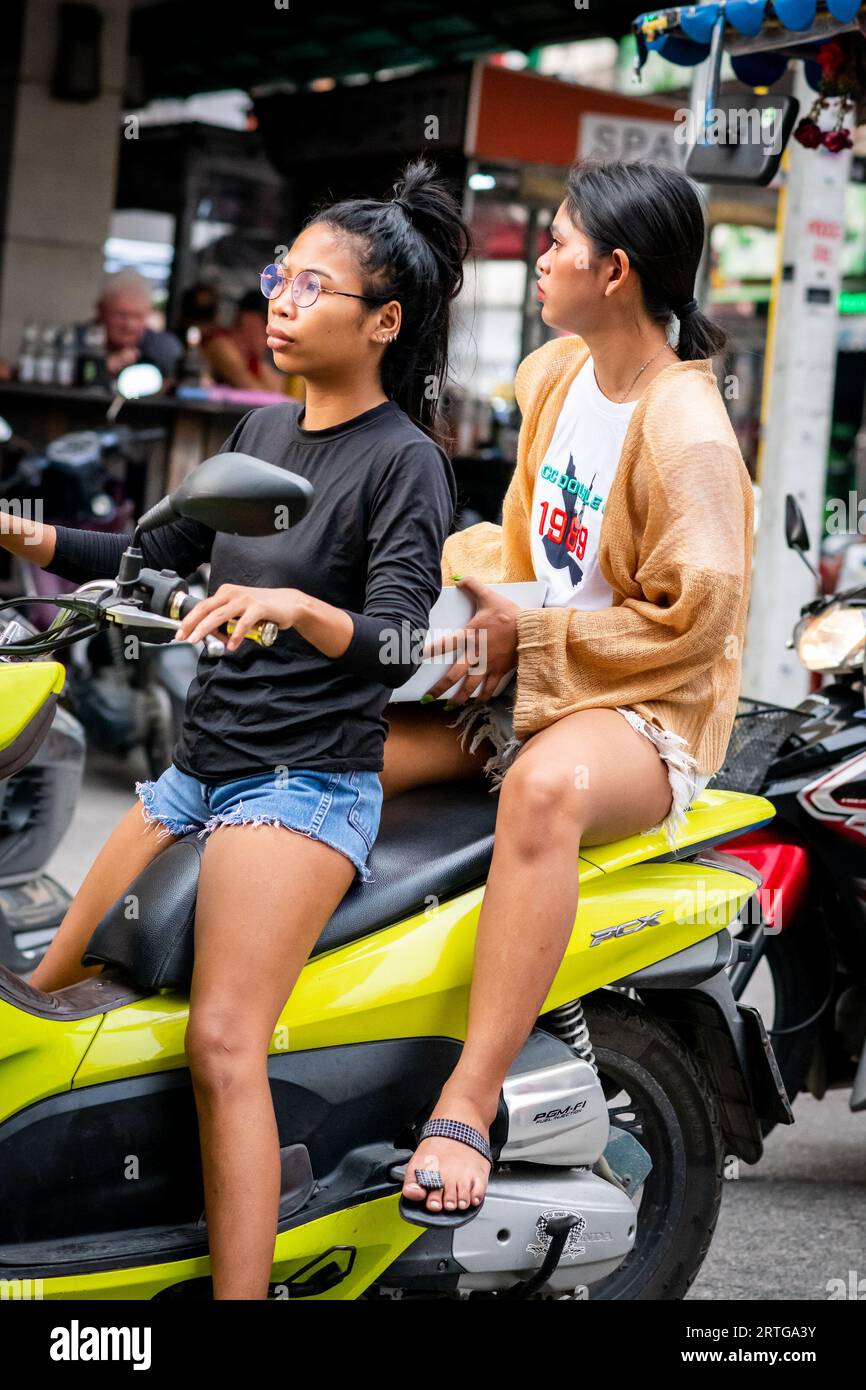 Local Thai people, tourists and residents rush past the busy junction of Soi Buakhao and Soi Lengkee in Pattaya Thailand on mopeds and motorbikes. Stock Photo