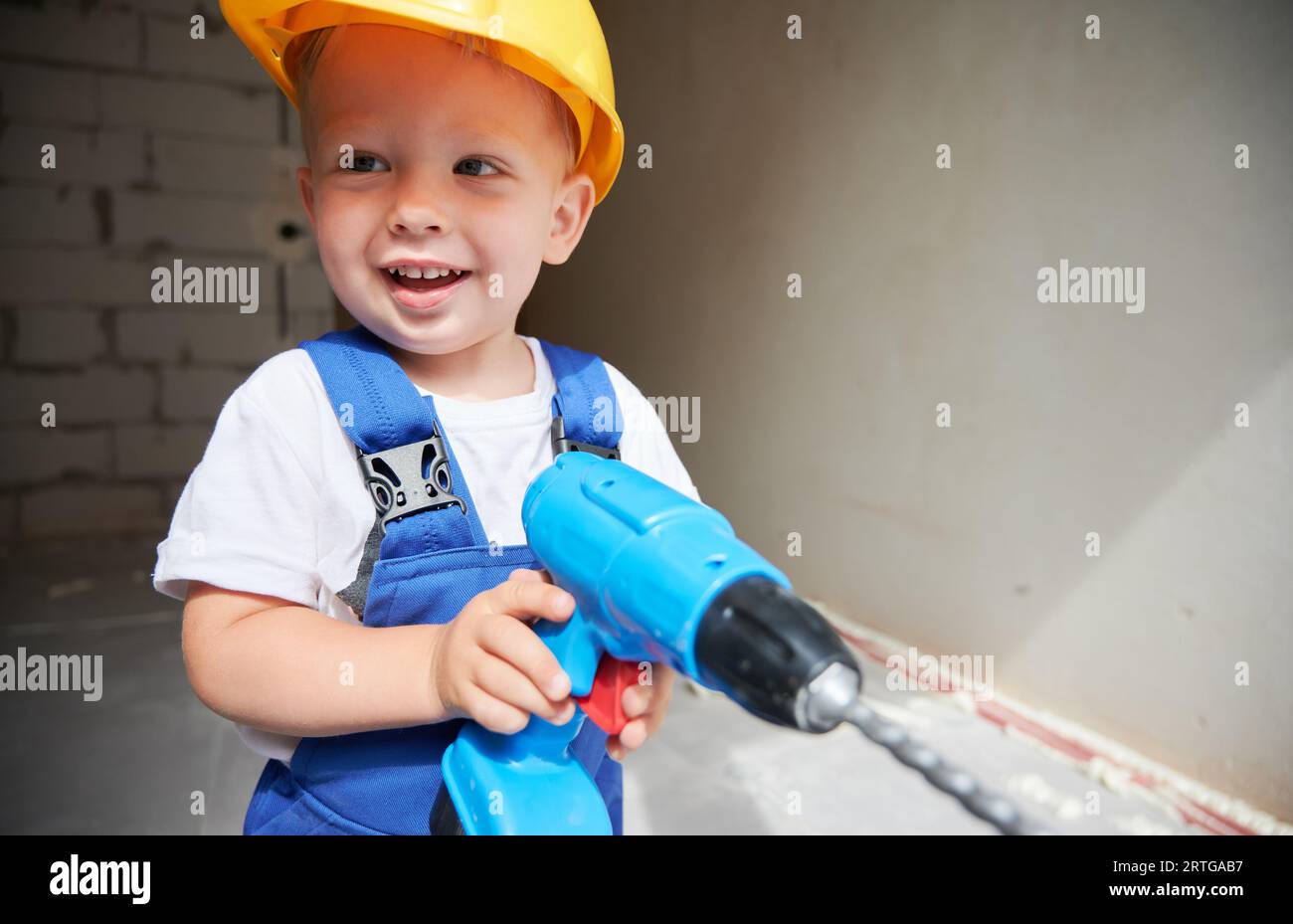 Cute baby boy construction worker looking aside and smiling while