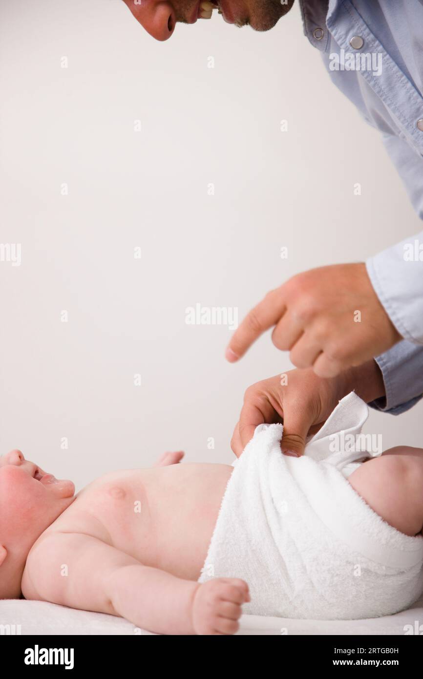 Man smiling and changing baby nappy Stock Photo