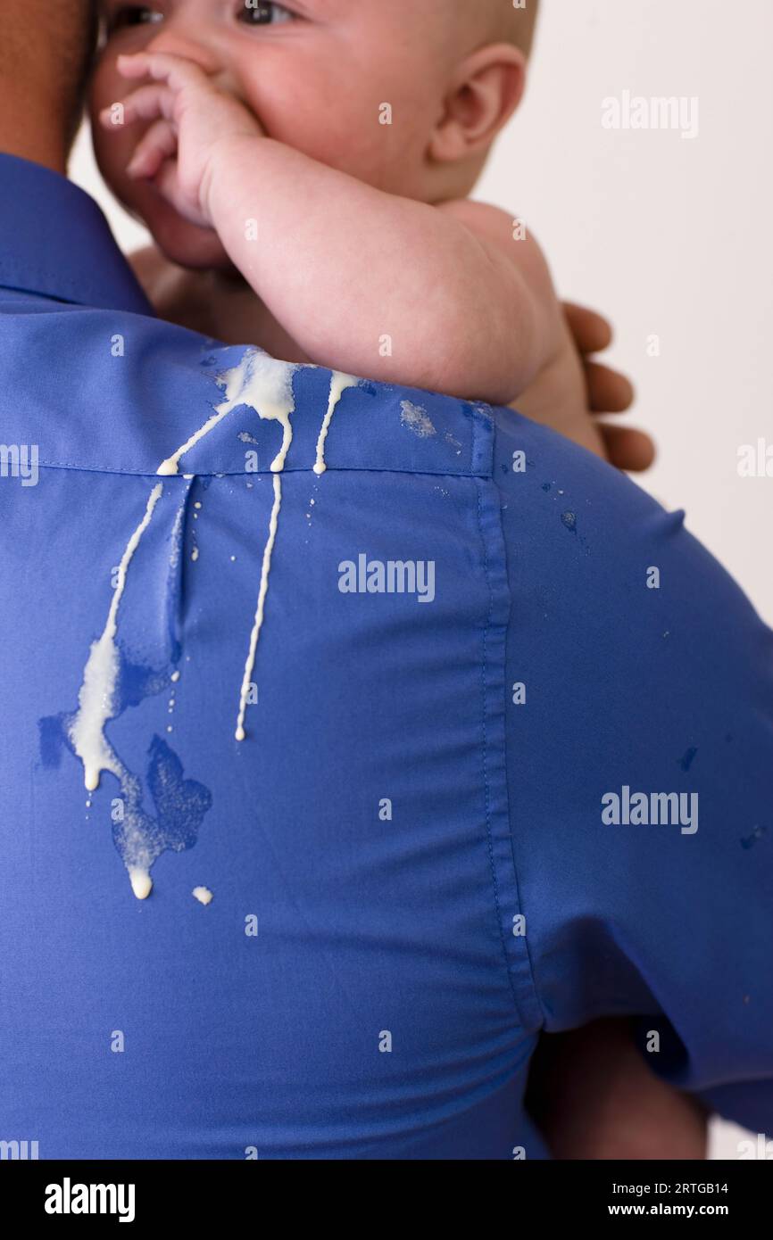 Back view of a man holding a baby with vomit on his back and shoulder