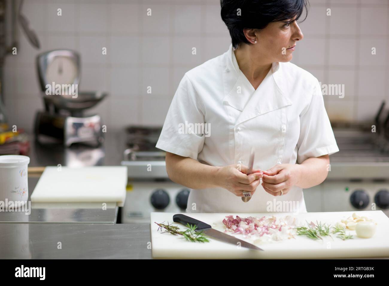 Woman chef peeling garlic with a knife looking to one side Stock Photo ...