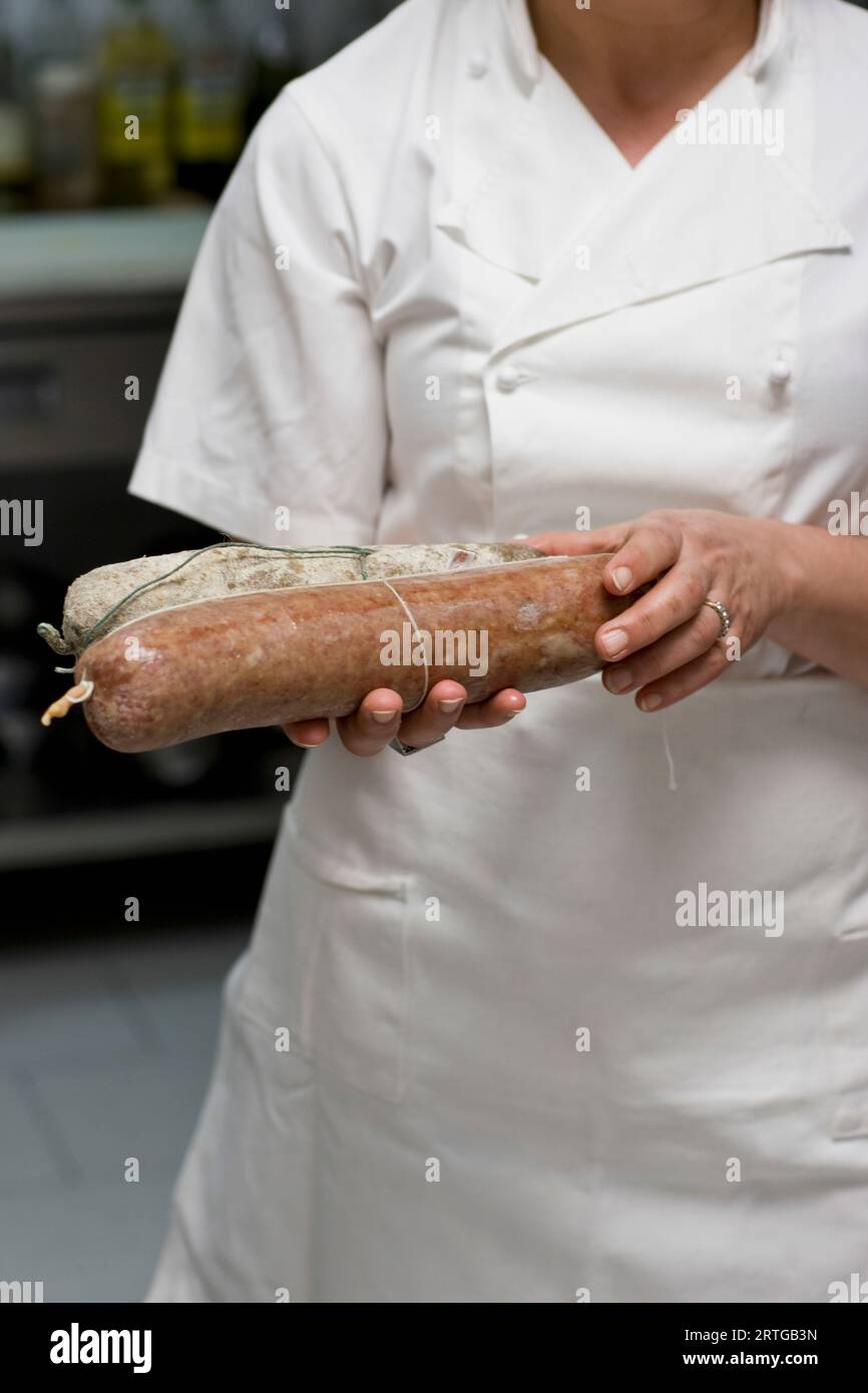 Woman chef holding salami Stock Photo