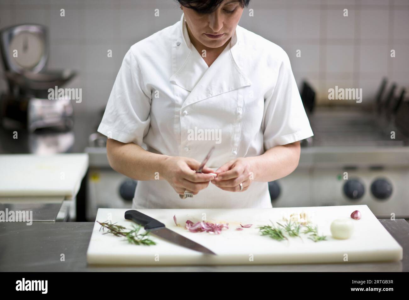 Woman chef peeling garlic with a knife Stock Photo - Alamy