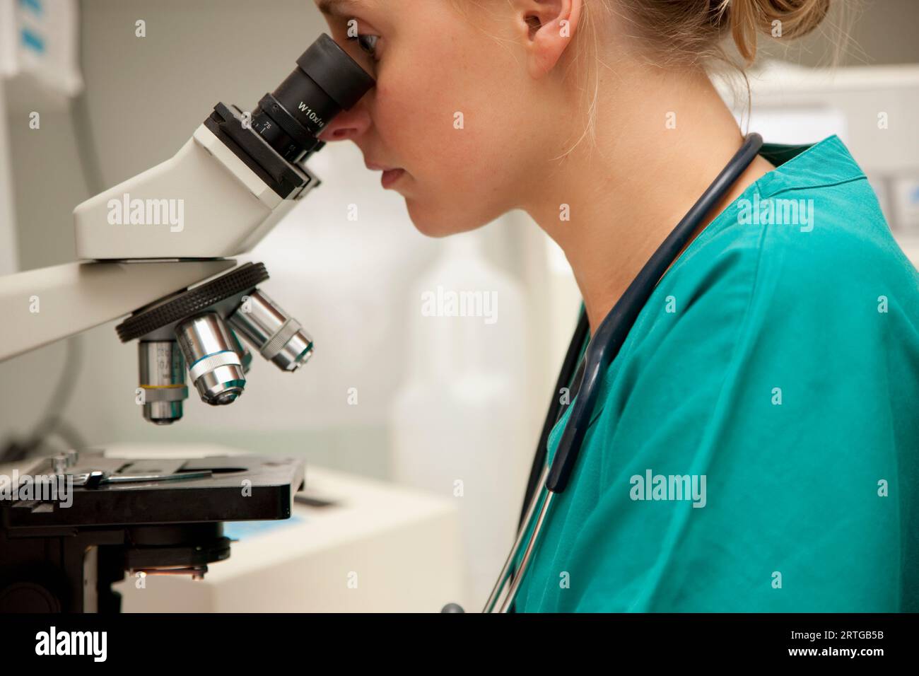 Lab technician looking into microscope Stock Photo