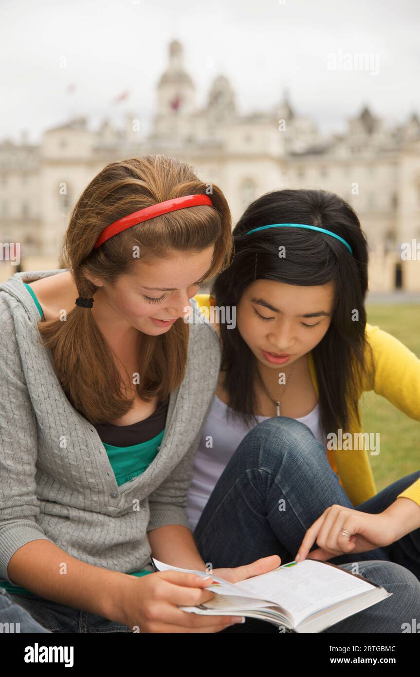 Two teenaged girl reading a book in front of  London Horse Guards Parade Stock Photo