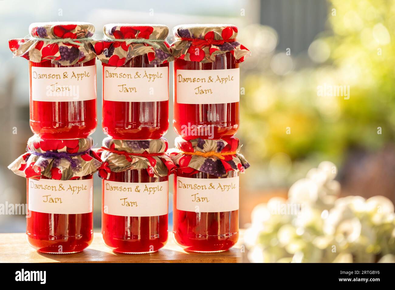 Jars of homemade Damson and Apple jam. The glass jars have clear handwritten labels and each jar has a cloth topping. Stock Photo