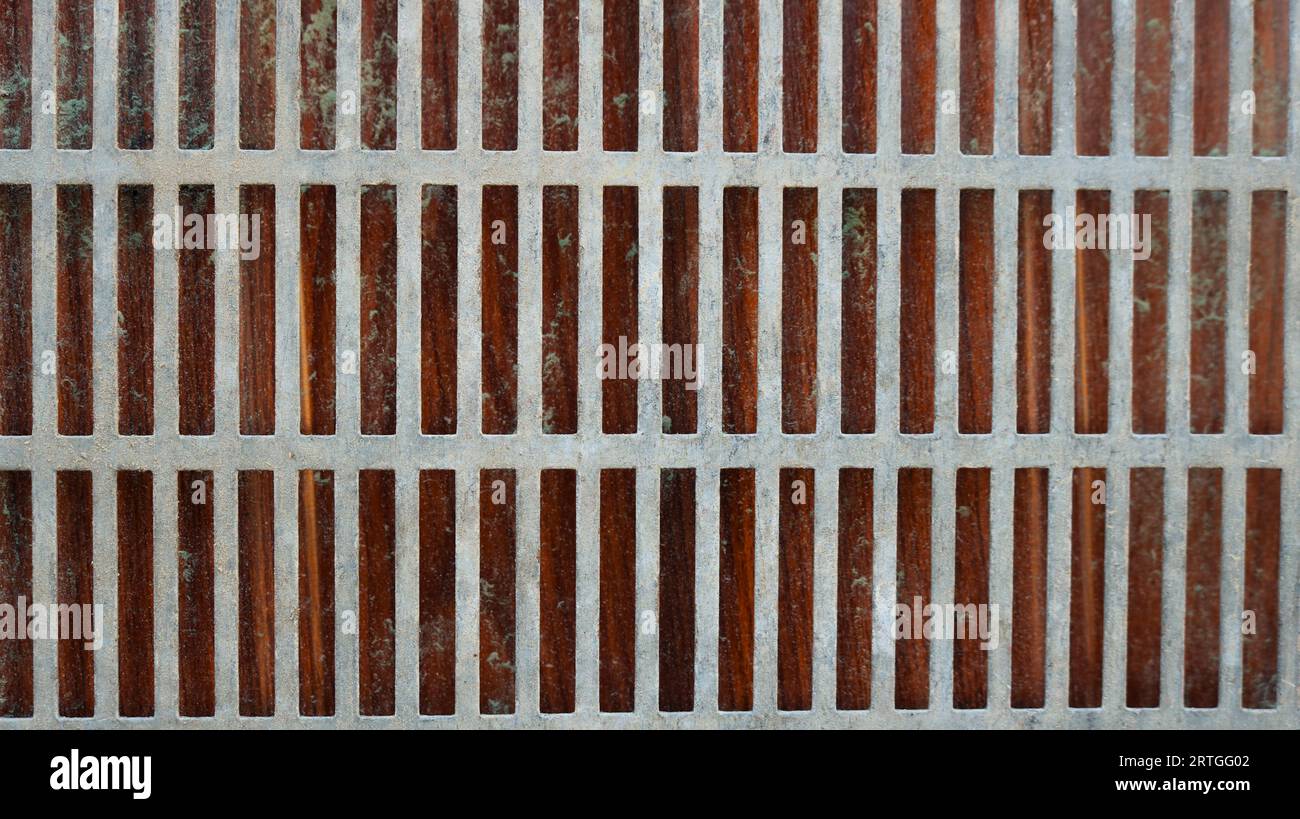 lattice metal mesh of long strips on a dark dirty background as a grunge graphic resource, iron mesh with thick crossbars with a dark backdrop Stock Photo