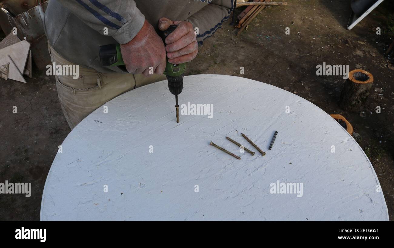 screwing bolts into the textured surface of a white round table, making