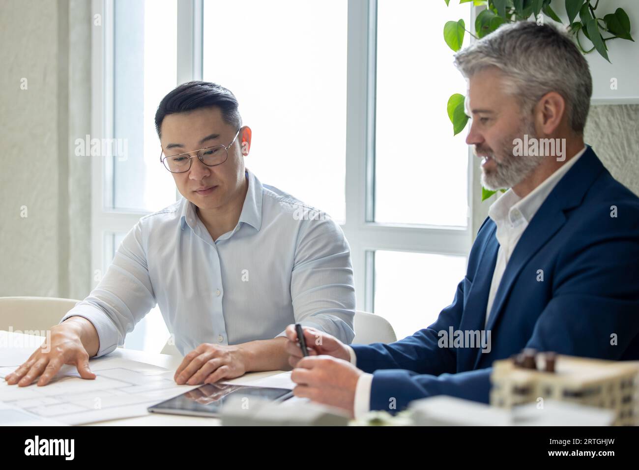 Men architects working on construction plans, engineers discussing on project in office. Stock Photo