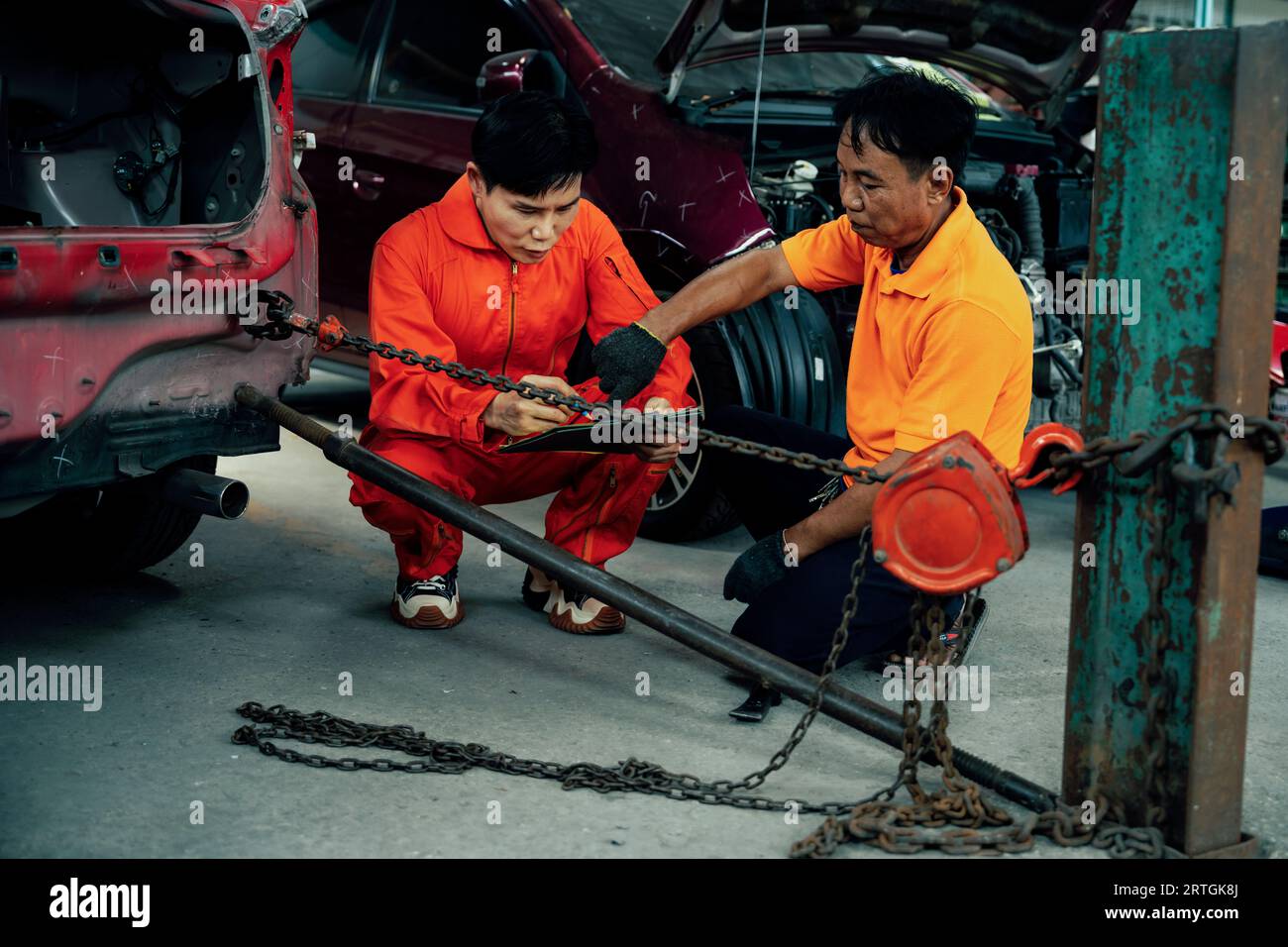 Mechanic testing strength and reliability of chain hoist for car towing