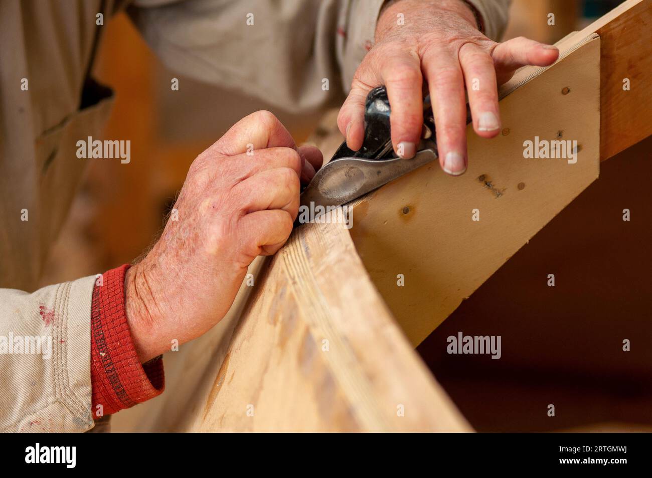 Hands of an artisan boat builder of wooden boats using traditional small plane Stock Photo