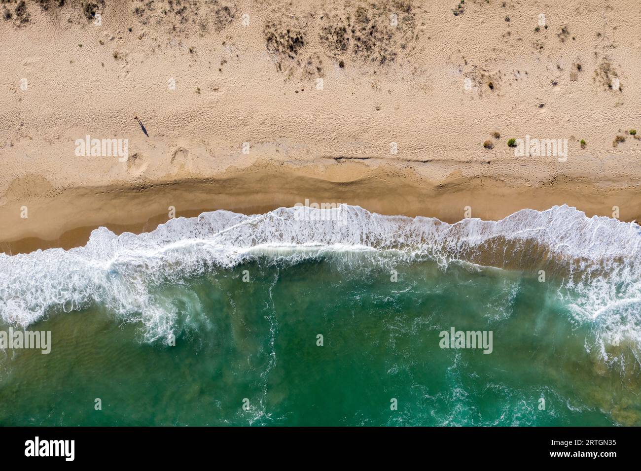 Aerial view of ocean waves washing a secluded sandy shoreline beach Stock Photo