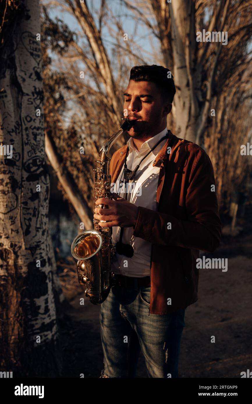 young musician playing the saxophone at sunset Stock Photo