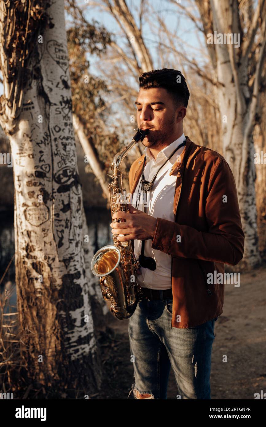 young musician playing the saxophone at sunset Stock Photo