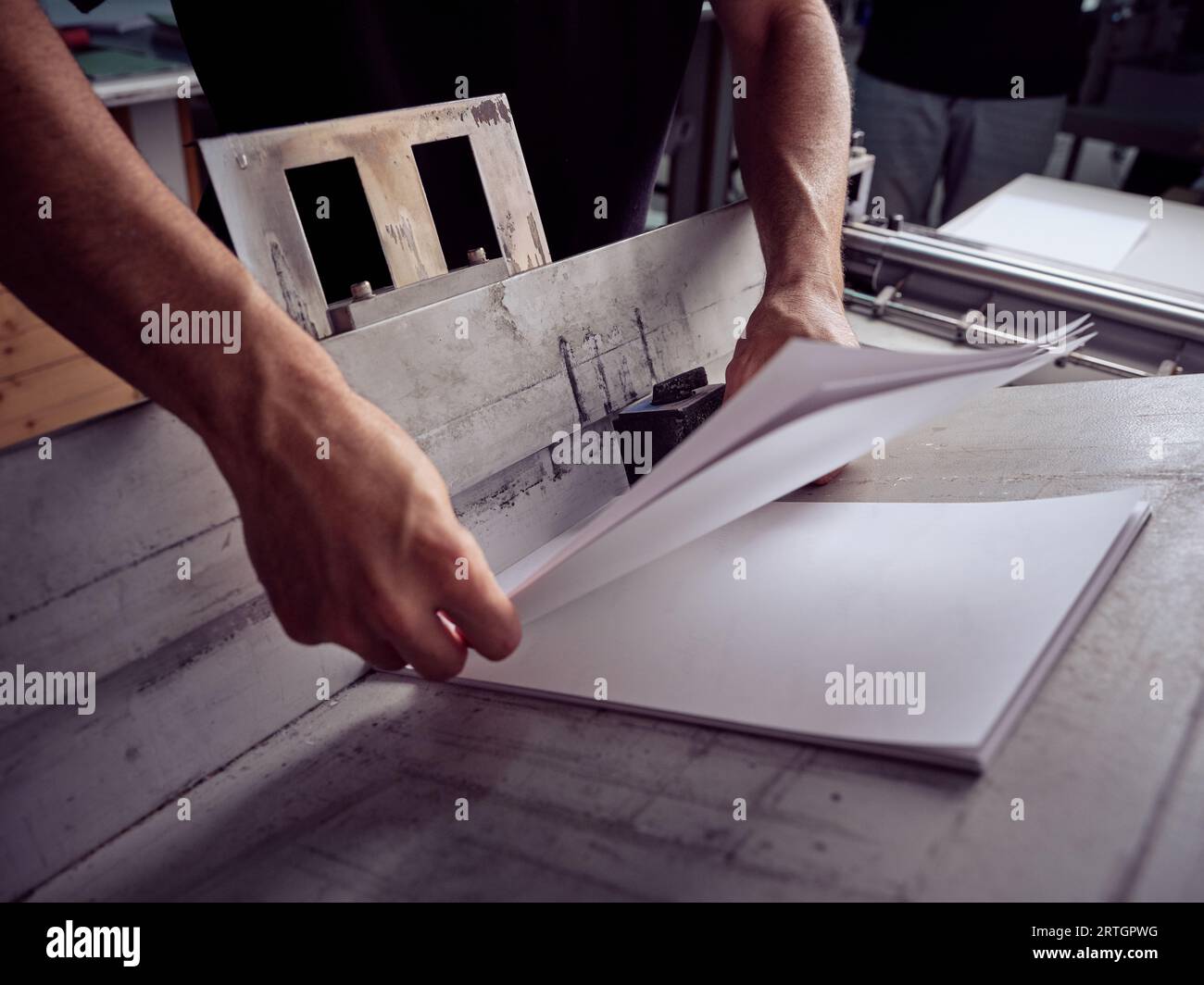 Unrecognizable man working with papers while standing at table and checking paper sheets in workshop Stock Photo