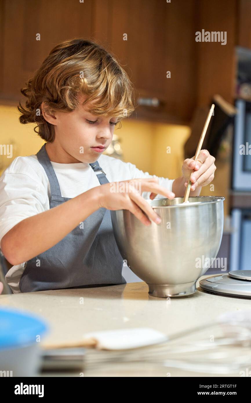 Stock vertical photo of a child mixing ingredients in a metal container