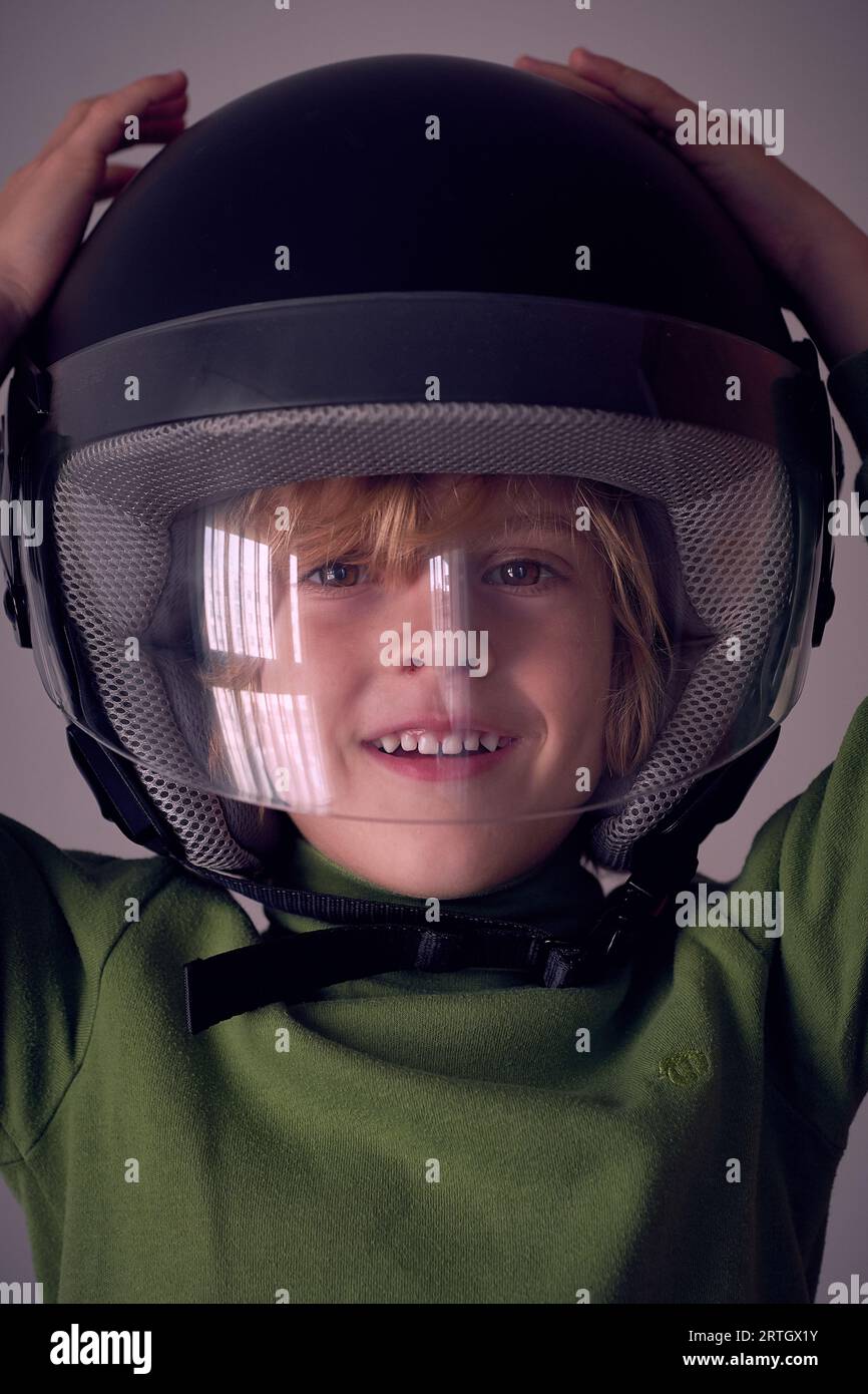 Cute little kid wearing big black protective helmet with transparent